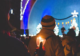Person holding a candle at the Candlelight Festival outside the bandshell